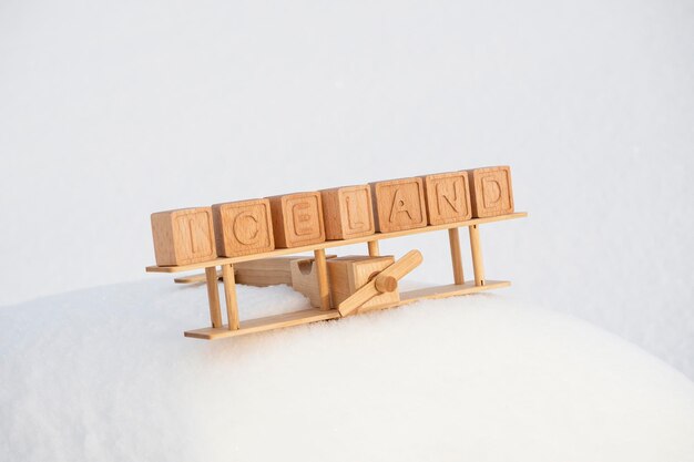 Foto een houten speelgoedvliegtuig en het land ijsland gemaakt van hun kubussen tegen de achtergrond van besneeuwde bergen het concept van reizen naar de noordelijke landen van europa naar ijsland
