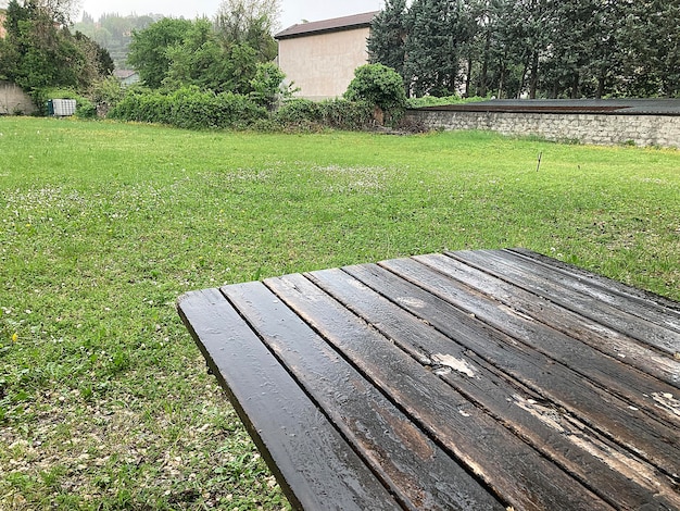 Een houten tafel in een tuin met een groen gazon op de achtergrond.