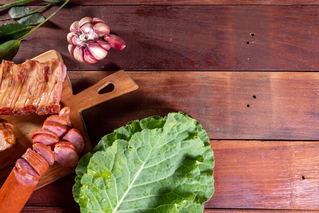 Een houten tafel met daarop een houten snijplank met groenten en knoflook.