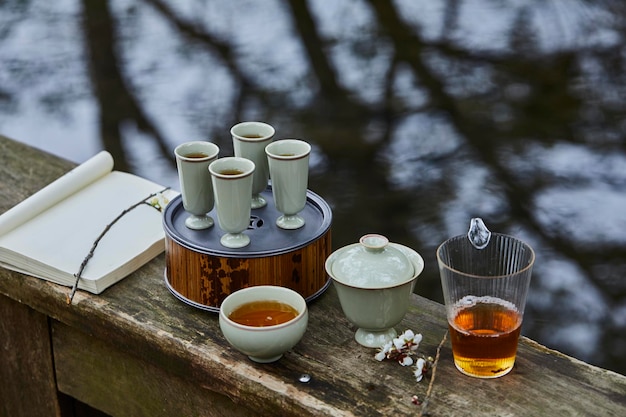 Een houten tafel met daarop een kopje thee en een glas thee Drink thee en dompel je onder in de natuur