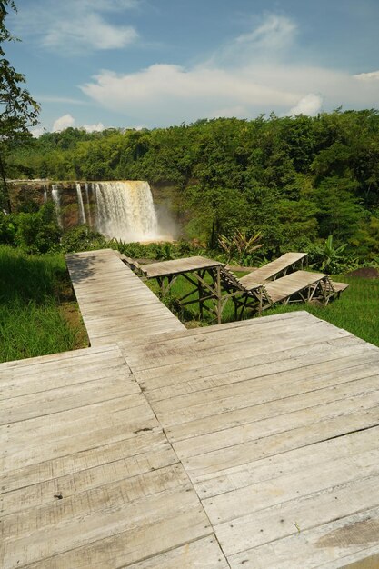 Foto een houten terras met een tafel en banken voor een waterval