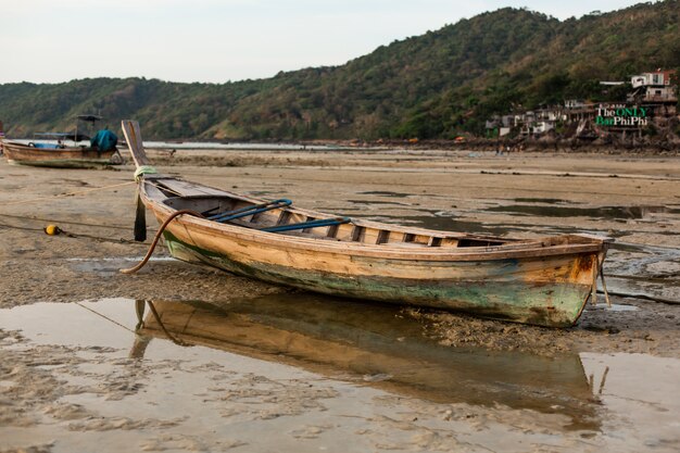 Een houten vissersboot zat bij eb op de zandbodem van de oceaan.