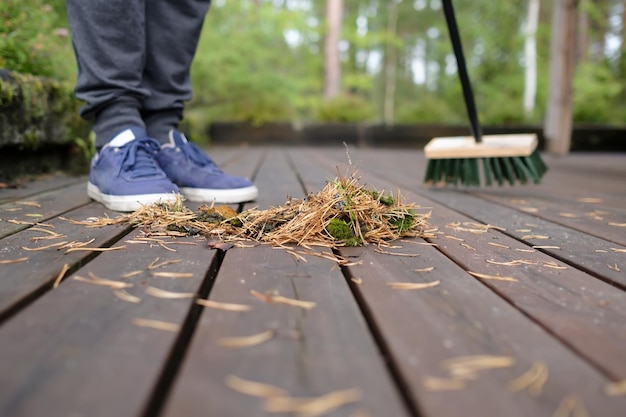 Een houten vloer vegen met een dweil van dennennaalden