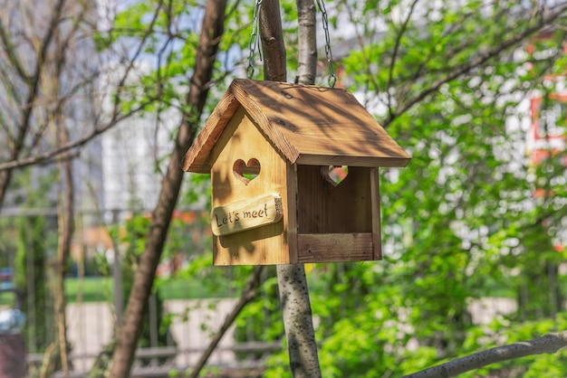 Een houten vogelvoeder op een achtergrond van jonge groene bladeren Prachtig natuur behang buiten stijl concept