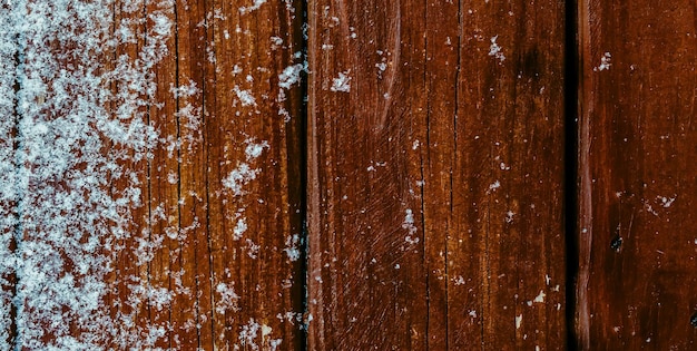 Een houten wand met sneeuw erop