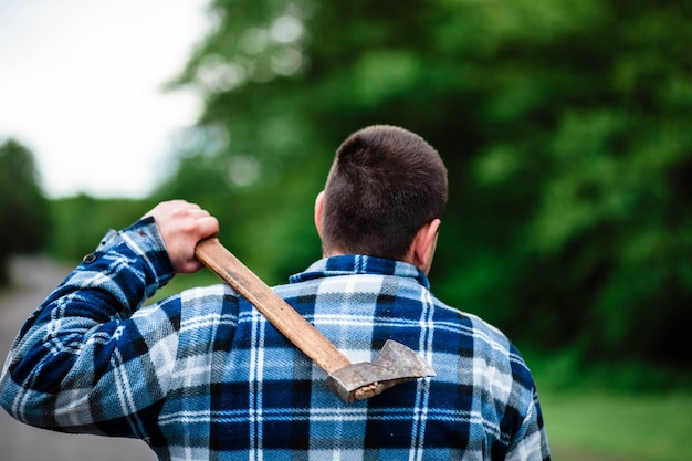 Een houthakker werkt in het bos Houthakker met een bijl in het zomerbos De houthakker houdt een bijl vast De houthakker houdt een bijl op zijn rug De houthakker toont de klasse Bijl in de hand