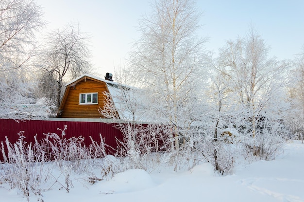 Een huis gemaakt van hout in de winter in het bos onder de sneeuw.