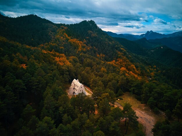 Een huis in de bergen met een bewolkte lucht op de achtergrond