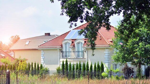 een huis met een rood dak en een blauwe lucht met een zonnepaneel op het dak.