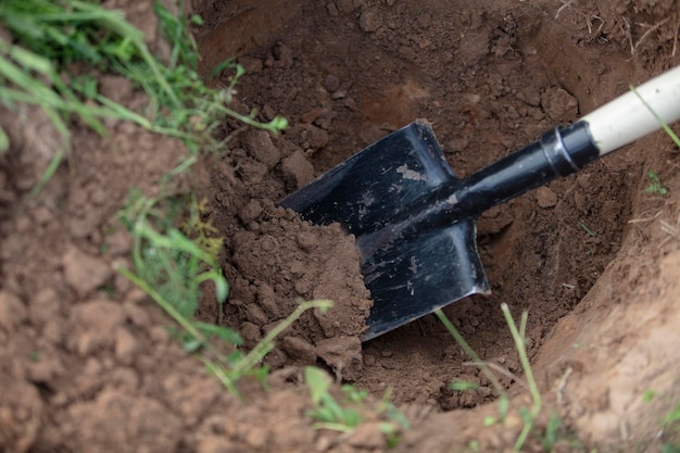 Een ijzeren schop in een gat in de grond Handgrondwerken