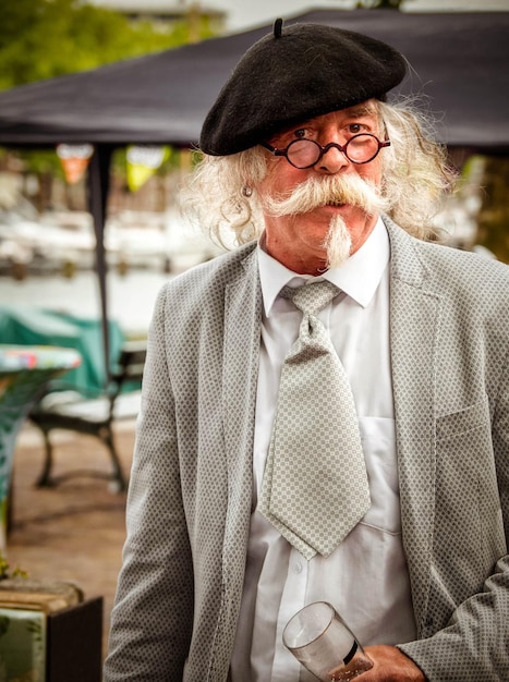 Een imposante man met een snor in een baretbril in een straatcafé in Nederland