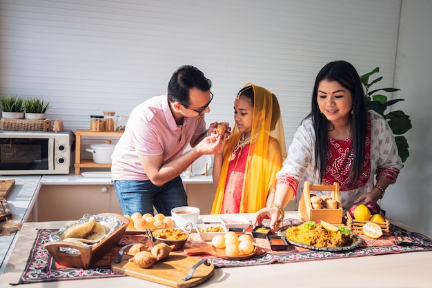 Foto een indiase familie die in de keuken staat ze eten en bereiden veel voedsel op tafel voor familie en indiase voedselconcept