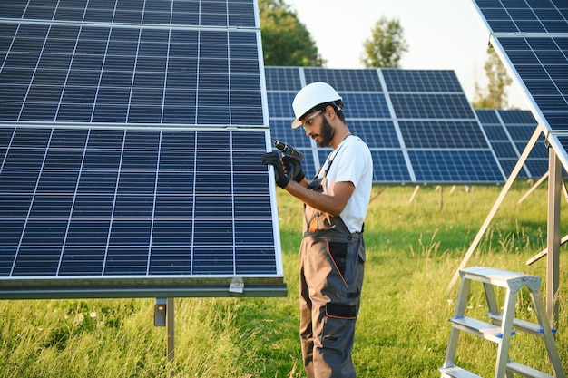 Een Indiase mannelijke arbeider werkt aan het installeren van zonnepanelen in een veld