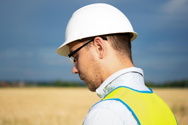 Een ingenieur met een tablet in zijn handen staat in het midden van een veld en controleert de oogst