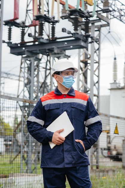 Een ingenieur van een elektrisch onderstation inspecteert moderne hoogspanningsapparatuur in een masker