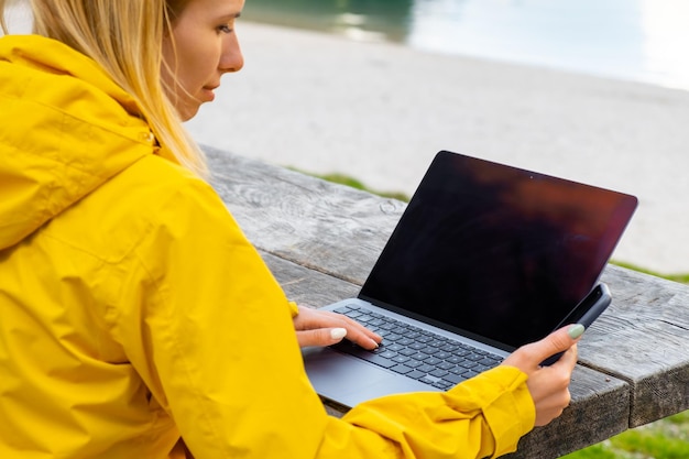 Een inspirerende vrouw glimlacht en scrolt over het scherm van haar smartphone en gebruikt sociale media op laptop