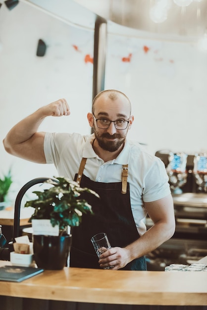 Een interessante ober pronkt met zijn biceps terwijl hij aan de bar werkt?