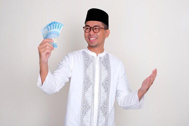 Een islamitische man die een gelukkig gezicht toont als hij naar geld staart dat hij vasthoudt