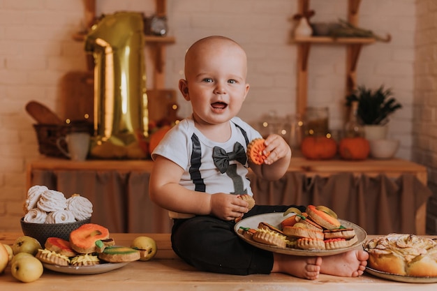 Een jaar oude baby eet zelfgemaakte beschilderde peperkoek. eerste verjaardag in een feestelijke sfeer. gezonde snack voor kinderen. kleine jongen zit aan de keukentafel. Hoge kwaliteit foto