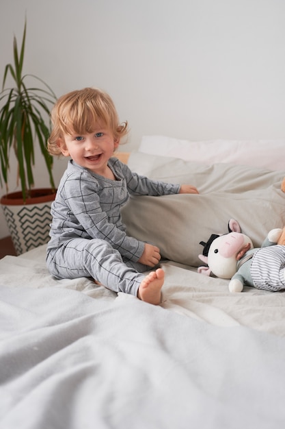 Een jaar oude jongetje spelen en plezier maken op het bed thuis, lifestyle foto