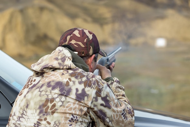 Een jager in camouflage op de schietbaan kalibreert het wapen Een man schiet op doelen