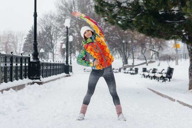 Een jong atletisch meisje sport op een ijzige en besneeuwde dag. Geschiktheid, het lopen.