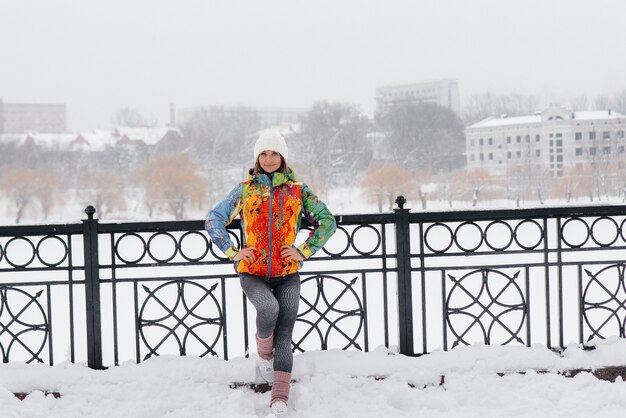 Een jong atletisch meisje stelt op een ijzige en sneeuwdag. Fitness, hardlopen.