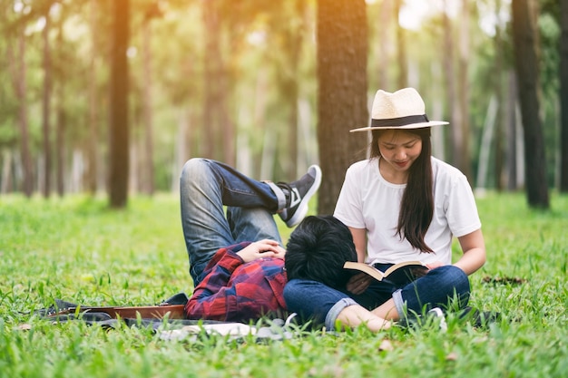 Een jong aziatisch minnaarpaar dat boek leest en samen in het park ligt