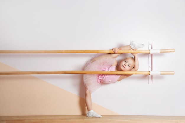 Een jong ballerinameisje in een roze jurk is bezig met een balletstudio