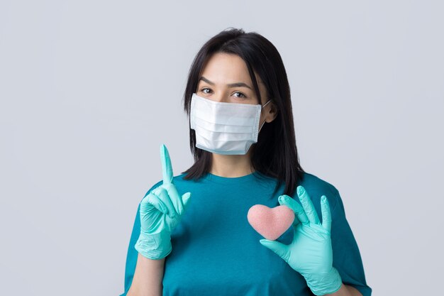 Een jong donkerbruin meisje met een beschermend medisch masker met een roze hart symboliseert het leven