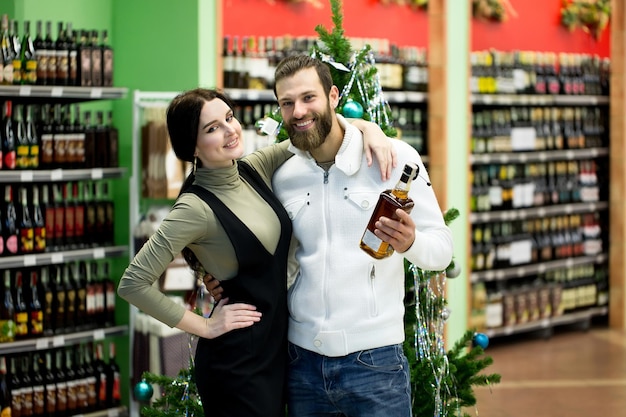 Een jong gezin, een man en een vrouw kiezen alcohol in een grote supermarkt.