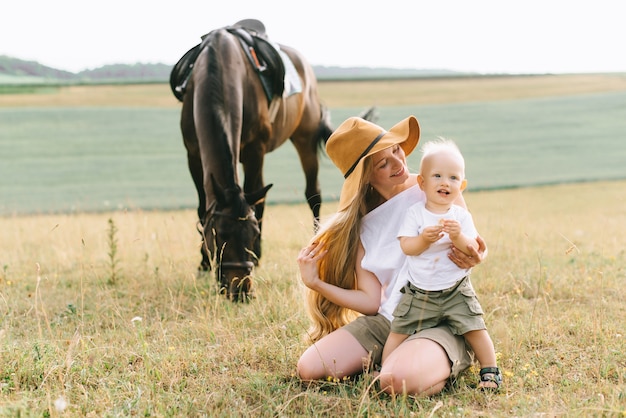 Een jong gezin heeft plezier in het veld. Ouders en kind met een paard