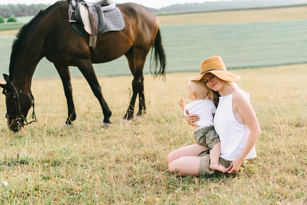 Een jong gezin heeft plezier in het veld. Ouders en kind met een paard