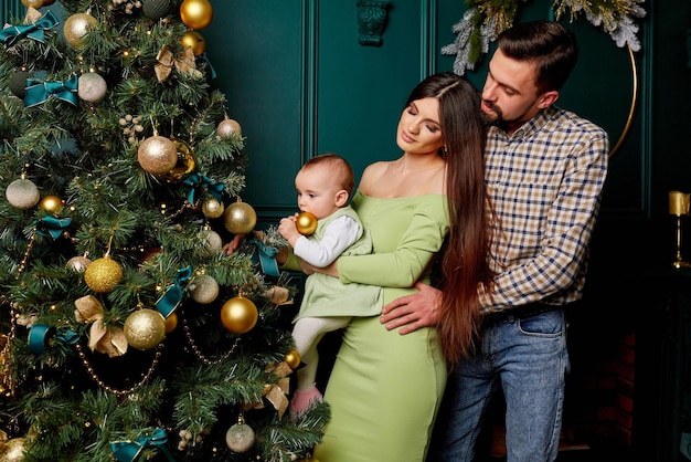 Een jong gezin met een baby bij de kerstboom Een moeder houdt haar dochtertje in haar armen