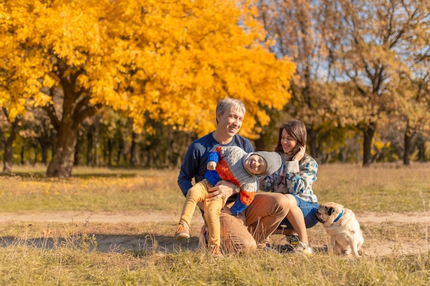 Een jong gezin met een klein kind en een hond brengen samen tijd door voor een wandeling in het herfstpark