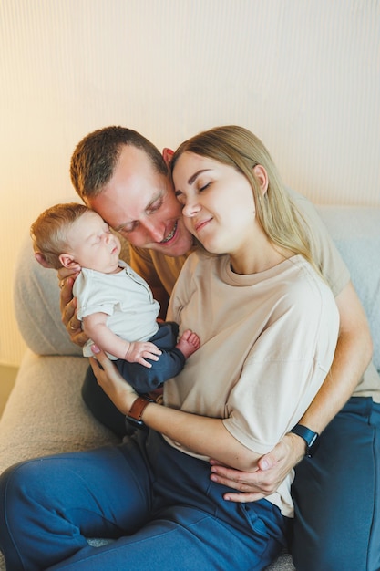 Een jong gezin met een pasgeboren baby Gelukkige moeder en vader kussen hun kind Ouders en een glimlachend kind in hun armen