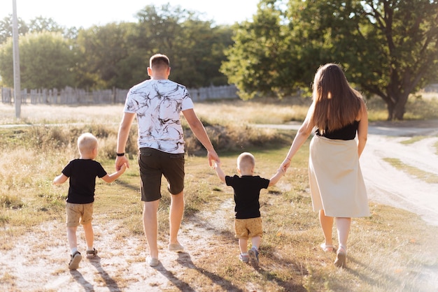 Een jong gezin met twee kinderen wandelt in de zomer buiten de stad door de natuur