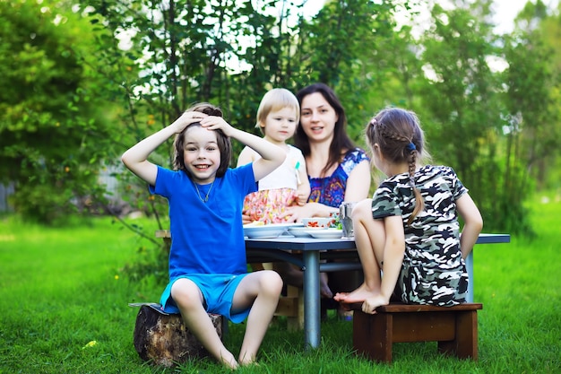 Een jong groot gezin bij een picknick op een zomerochtend. Een mooie moeder met kinderen ontbijt in het park.