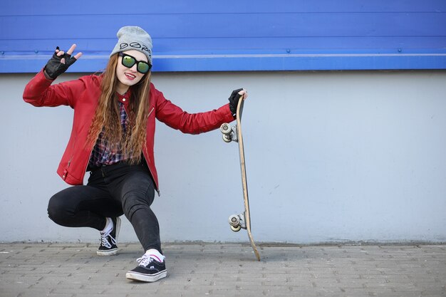 Een jong hipstermeisje berijdt een skateboard. Meisjes vriendinnen voor een wandeling in de stad met een skateboard. Lente sporten op straat met een skateboard.