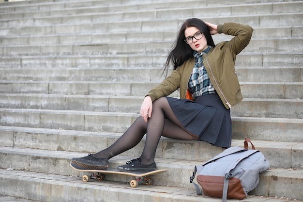 Een jong hipstermeisje rijdt op een skateboard Meisjesvriendinnen voor een wandeling in de stad met een skateboard Lentesporten op straat met een skateboardxA