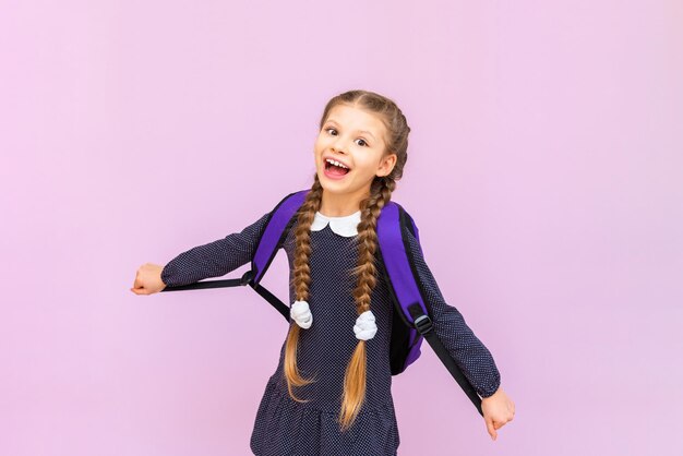 Een jong, jong schoolmeisje in een polkadot-jurk en met lange staartjes is erg blij en lacht