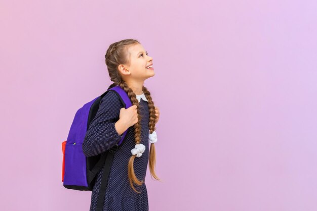 Een jong, jong schoolmeisje in een polkadot-jurk en met lange staartjes is erg blij en lacht