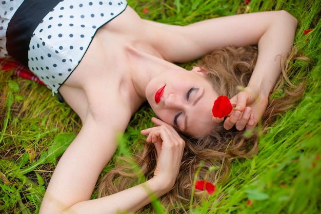 Een jong langharig meisje geniet van de kleuren van de natuur op een bloeiende papaverveld op een hete zomerdag.