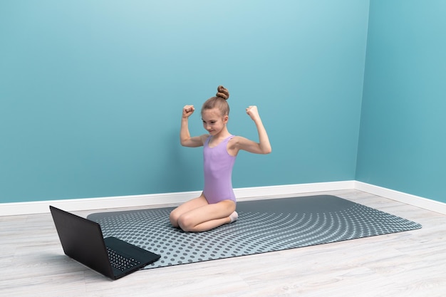 Een jong meisje doet gymnastiek voor een laptop Lessen thuis