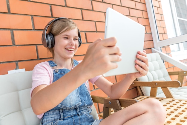 Een jong meisje geniet van het luisteren naar muziek op haar koptelefoon met tablet