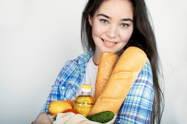 Een jong meisje in een blauw shirt heeft een stoffen tas met voedsel