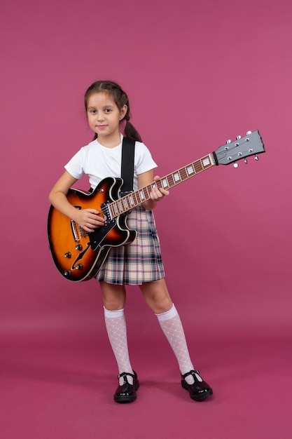 Een jong meisje in een schooluniform speelt een elektrische gitaar