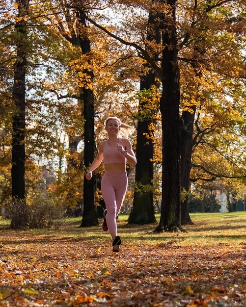 Een jong meisje in een sportuniform Sport Joggen in het herfstpark Geel gebladerte Actieve levensstijl Mens en natuur Gezonde levensstijl Hardlopen
