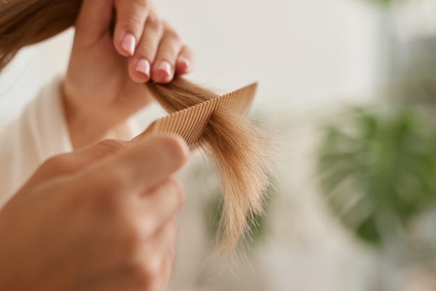 Een jong meisje in een witte jas verzorgt haar haar thuis