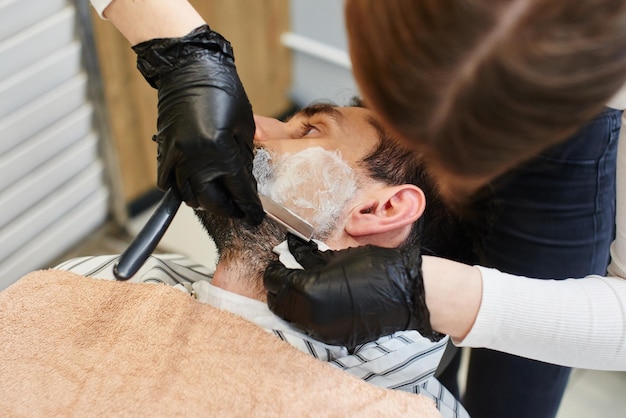 Een jong meisje Kapper scheert een baard, de man in de kapperszaak